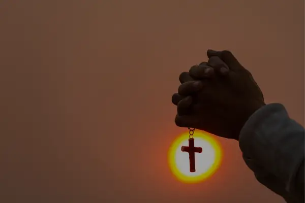 Pessoa segurando uma cruz em momento de oração, simbolizando a conexão entre fé e ansiedade na busca por paz interior.