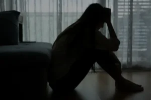 Pessoa deprimida sentada em um quarto escuro, refletindo sobre como confiar em Deus em meio à dor.