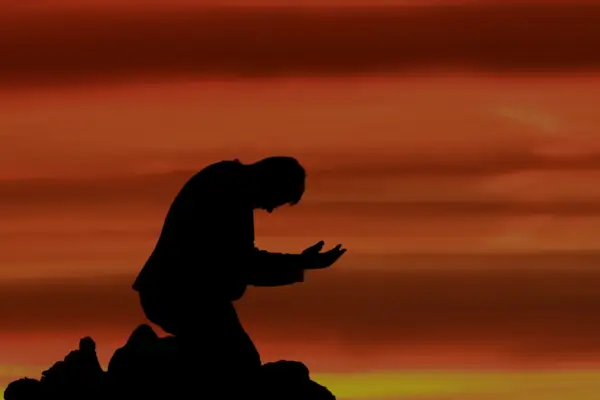 Pessoa de joelhos em oração, representando o perdão na Bíblia e a busca por restauração espiritual.