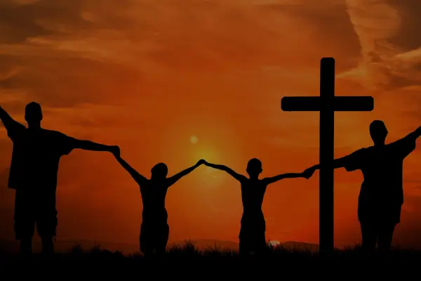 Quatro pessoas orando juntas em uma aula com cruz ao fundo, fortalecendo a fé em Deus
