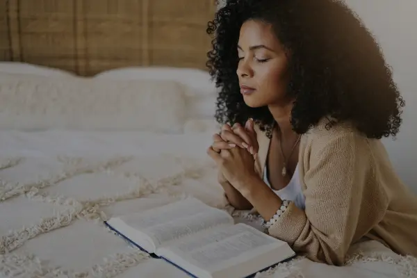 Mulher orando em silêncio com as mãos juntas, simbolizando como orar a Deus com fé e devoção.